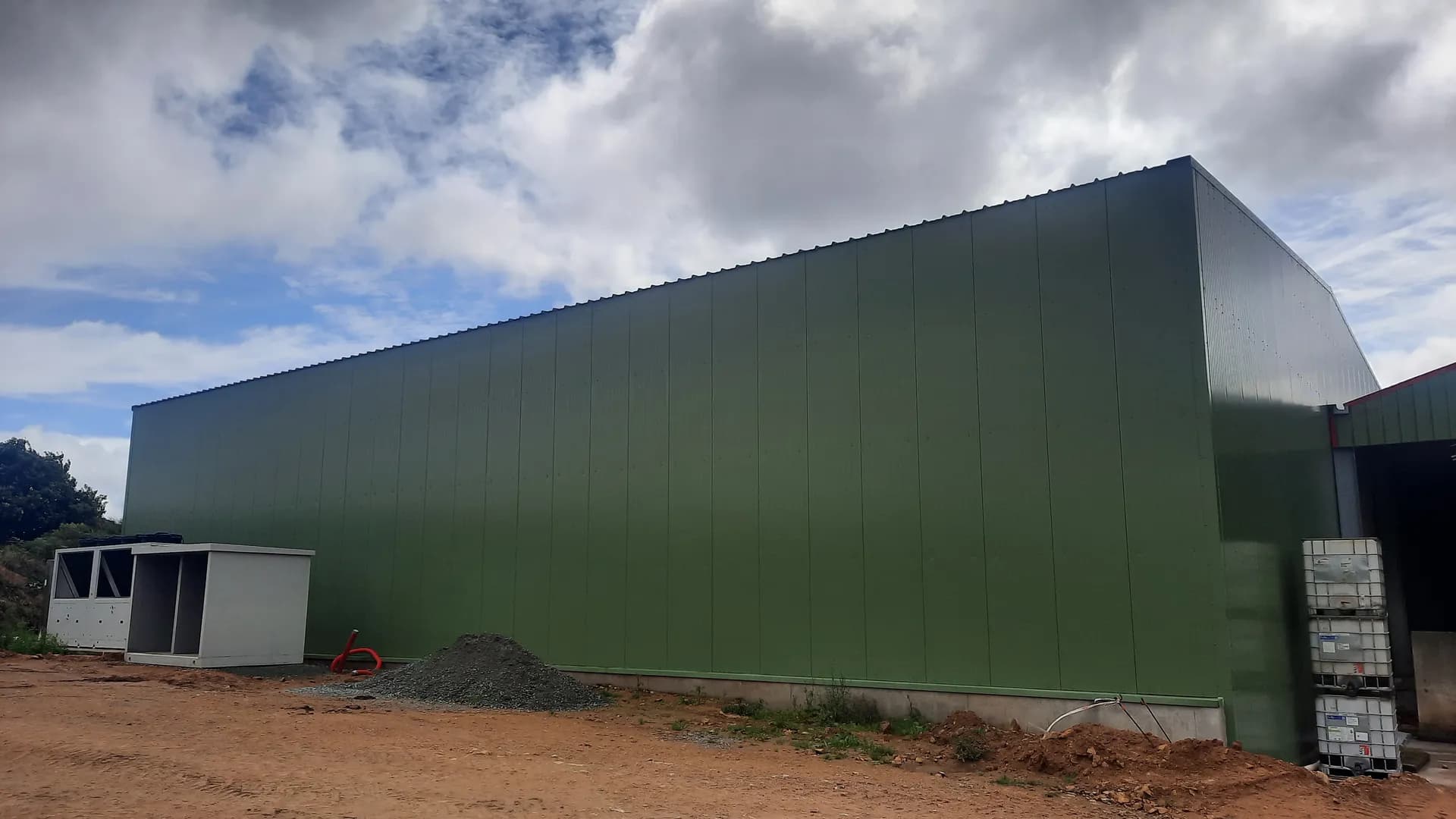Bâtiment réfrigéré de grande dimension en panneaux sandwichs verts sur une exploitation agricole du Finistère, avec les groupes de froid au pied du bardage