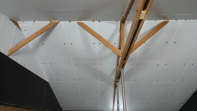 Panneaux isolants blancs posés sous la charpente en bois d'une salle d'élevage, lors de la rénovation de son isolation